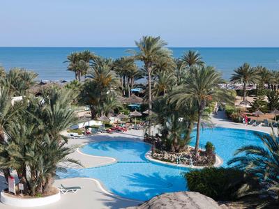 Una piscina tropicale con palme e vista sul mare in un resort hotel.