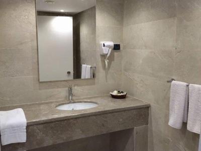 Schlichter Hotelbadezimmer mit Waschbecken, großem Spiegel, Haartrockner und Handtüchern.