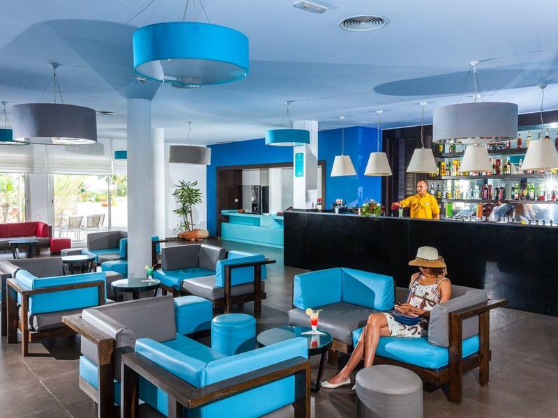 Moderne Hotellounge mit blauen Stühlen, Barbereich und entspannter Atmosphäre.