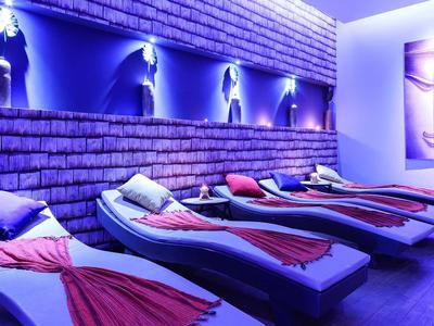 Ruheraum mit Liegen, blauer Beleuchtung und Wandbildern von Buddha-Gesichtern.