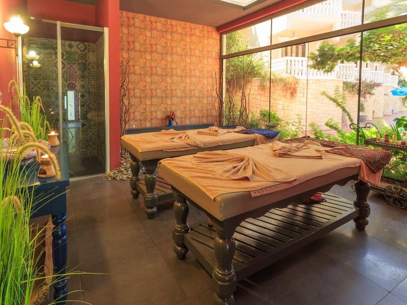 Ruhiger Raum mit zwei Massageliegen, Pflanzen, großem Fenster und warmem Licht für Entspannung.