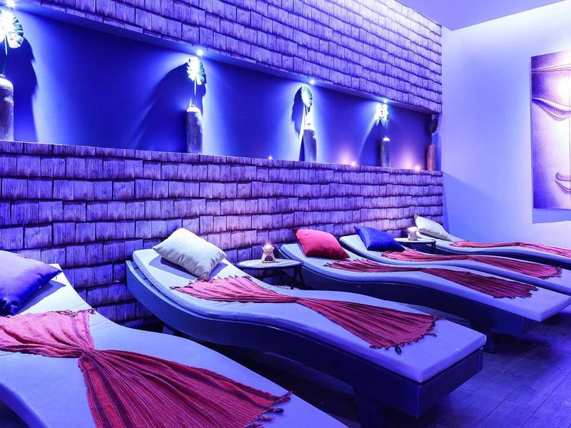 Ruheraum mit Liegen, blauer Beleuchtung und Wandbildern von Buddha-Gesichtern.