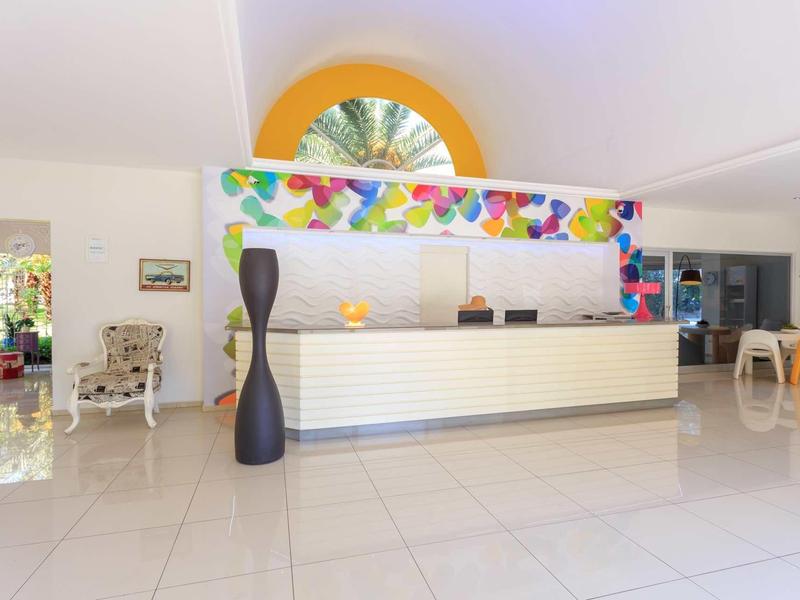 Hell gestaltete Hotelrezeption mit bunter Dekoration, weißen Fliesen und moderner Möblierung.