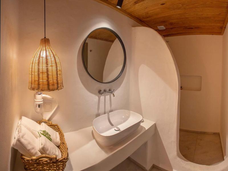 Modernes Badezimmer mit runder Wandspiegel, ovalem Waschbecken und geflochtener Lampe aus Holz.