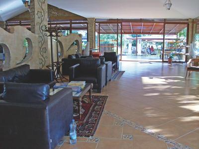 Moderní hotelová lobby s černými koženými křesly a velkým oknem propouštějícím denní světlo.