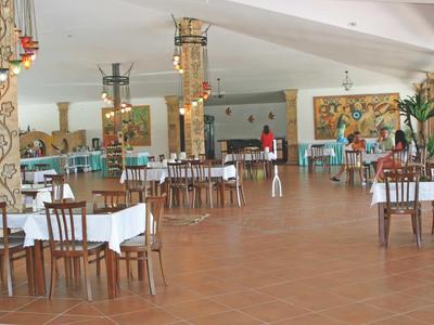 Prostorná světlá jídelna s bílými ubrusy a dřevěnými židlemi.