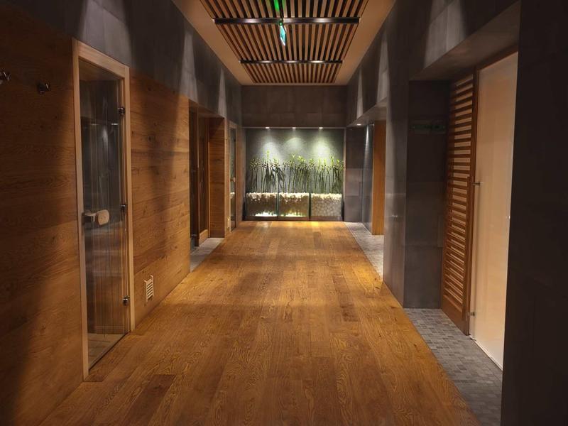 Pasillo de hotel con suelo y paredes de madera, iluminación tenue y ambiente acogedor.