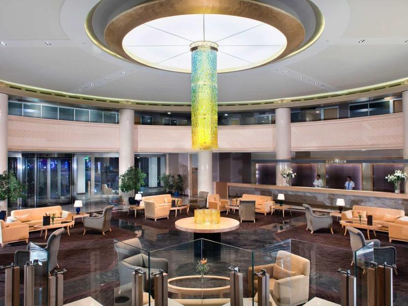 Amplia zona de salón de hotel con lámpara moderna y cómodas áreas para sentarse.