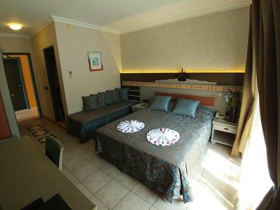 Bright hotel room with double bed, sofa, desk, and window with curtains