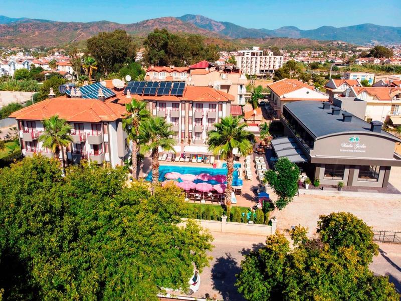 Complexe hôtelier avec piscine, palmiers et montagnes en arrière-plan sous un ciel clair