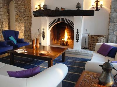 Gemütliches Wohnzimmer mit Kamin, weißen Sofas und blauen Akzenten in einem rustikalen Ambiente.