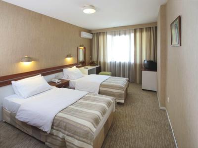 Ein schlicht eingerichtetes Hotelzimmer mit zwei Einzelbetten, Teppichboden und Fenster.