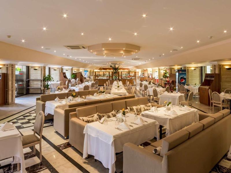 Elegancka restauracja hotelowa z nakrytymi stołami, wygodnymi miejscami i ciepłą atmosferą.