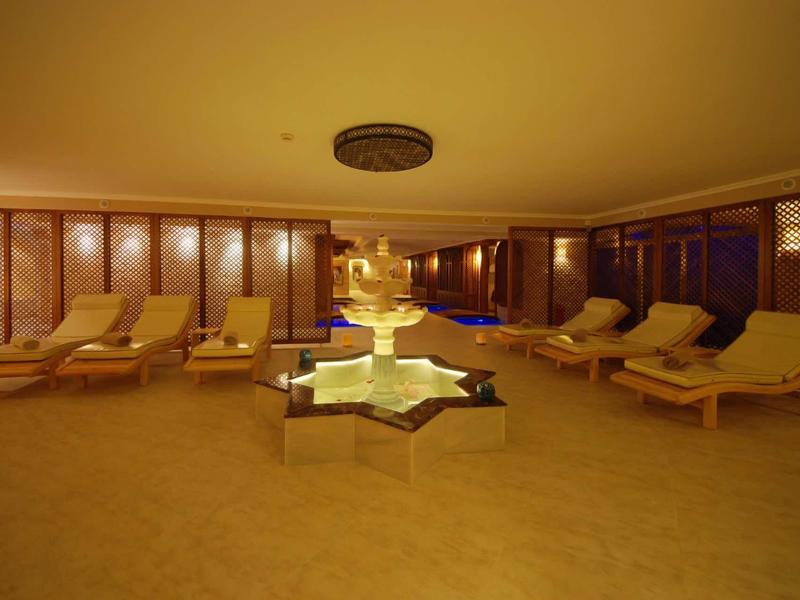 Spokojna strefa wellness z leżakami i podświetlaną fontanną na środku.