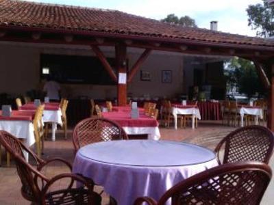 Balkon mit runden und rechteckigen Tischen, Stühlen aus Rattan und gedeckten Tischdecken.