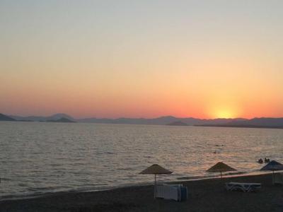 Sonnenuntergang über dem Meer mit ruhigem Strand und Sonnenschirmen.