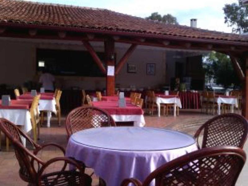 Balkon mit runden und rechteckigen Tischen, Stühlen aus Rattan und gedeckten Tischdecken.