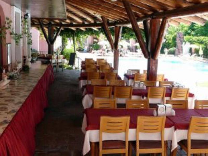 Überdachter Außenbereich mit Holzdach, mehreren Holztischen und Stühlen neben einem Schwimmbad.