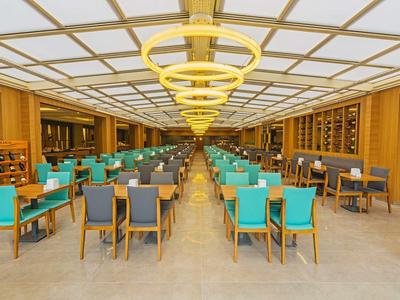 Moderner Restaurantraum mit Holzvertäfelung, vielen Tischen und Stühlen in Grün und Grau.