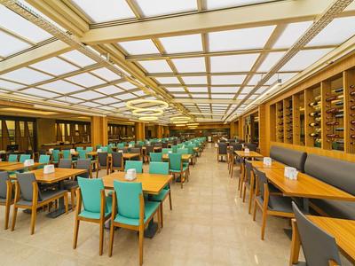 Bright, modern restaurant with turquoise and wooden seating, large windows, and spacious layout.