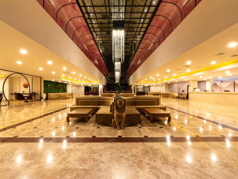Wide hotel lobby with shiny marble floor, comfortable seating, and warm lighting.