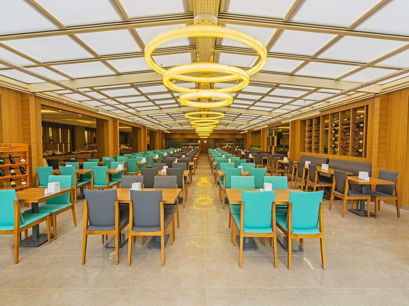 Modern restaurant with turquoise and gray chairs and light wooden paneling.