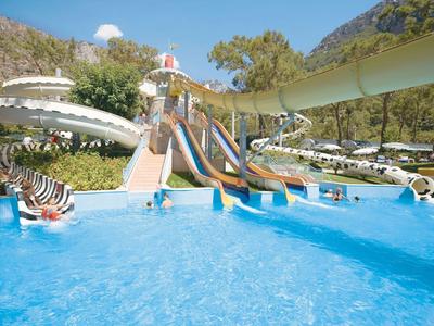 Mehrere bunte Wasserrutschen führen in einen klaren blauen Pool in einer Freizeitpark-Umgebung.
