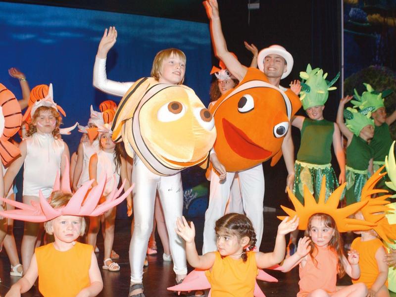 Kinder in bunten Meeres-Tierkostümen auf einer Bühne bei einer Theateraufführung.