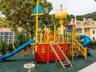 Colorful children's play ship with slides and climbing structures on soft outdoor flooring.