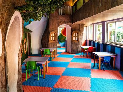 Colorful kids' playroom with tables, chairs, and soft foam flooring in a hotel.
