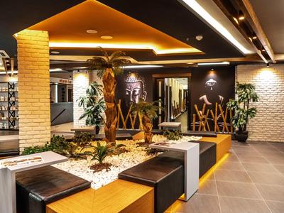 Modernly lit hotel lounge area with seating and plants in the center.