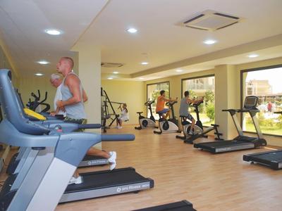 Ein moderner Fitnessraum mit Laufbändern und Trainingsgeräten, mit großen Fenstern und hellem Holzfußboden.