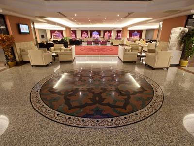 Spacious hotel lobby with marble floor and seating areas under warm lighting.