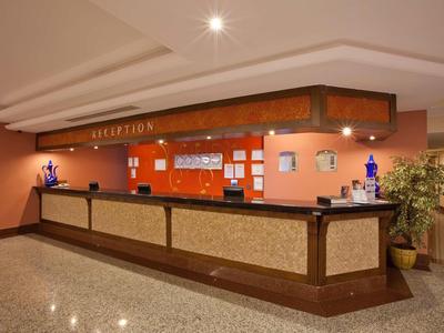 Reception desk with wooden counter, warm wall colors, and decorative lighting in a hotel.