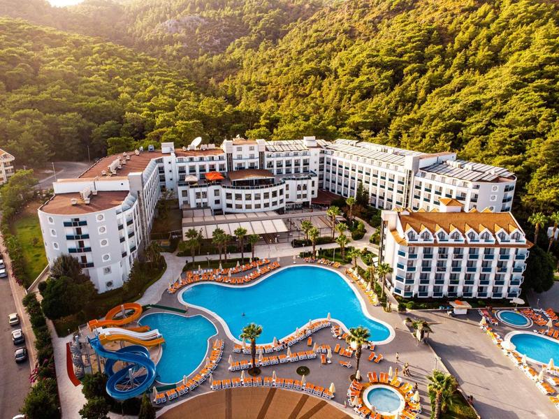 Large hotel resort with multiple pools, water slides, and surrounded by wooded hills.