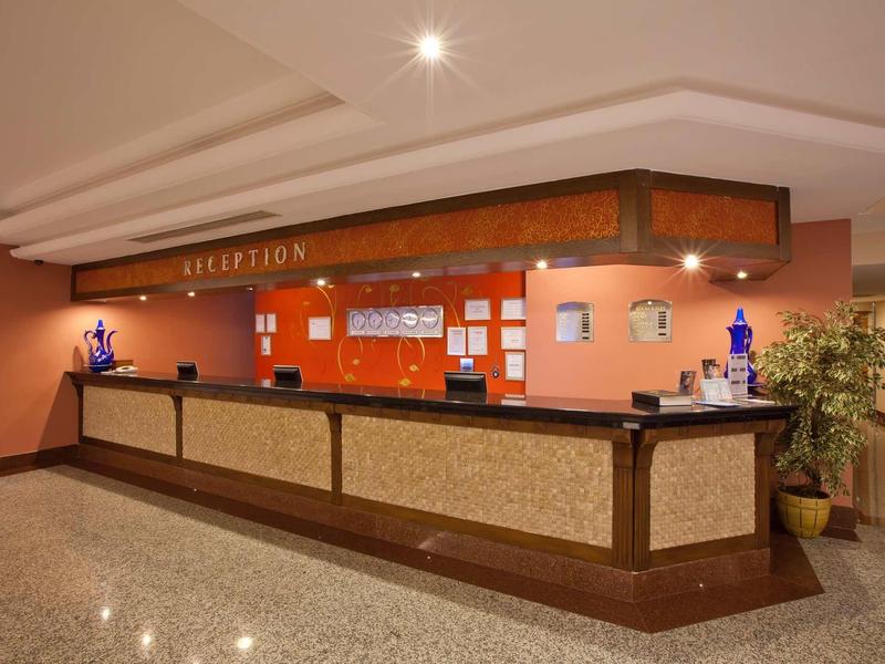 Reception desk with wooden counter, warm wall colors, and decorative lighting in a hotel.