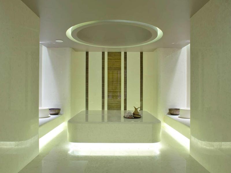 Moderní koupelna s osvětlenou vanou uprostřed a minimalistickým bílým designem.