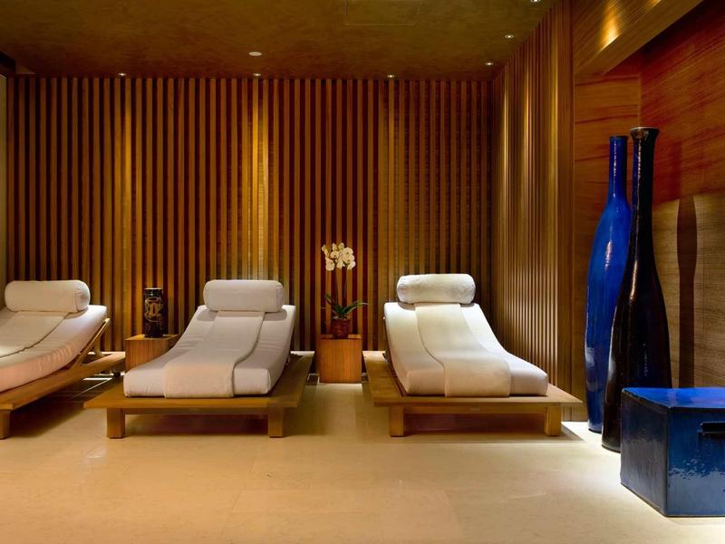 Pohodlná lehátka v hotelovém spa s dřevěnými stěnami a tmavě modrými dekoracemi.