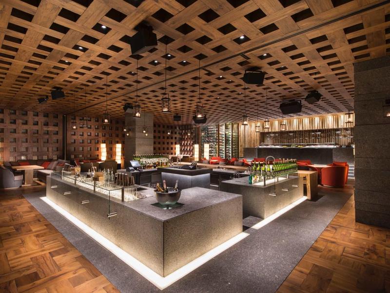 Moderní interiér elegantní restaurace s teplým osvětlením a stylovými stoly.