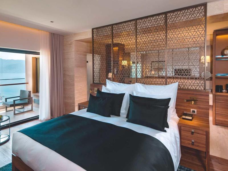 Moderní hotelový pokoj s manželskou postelí, balkonem a výhledem na moře.