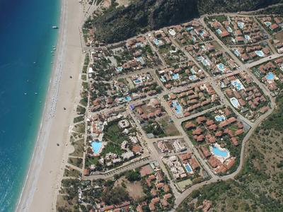 Luchtfoto van een kustplaats met strand, hotels en blauwe zee.