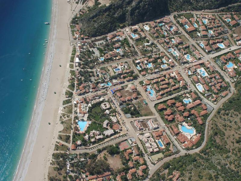 Luchtfoto van een kustplaats met strand, hotels en blauwe zee.