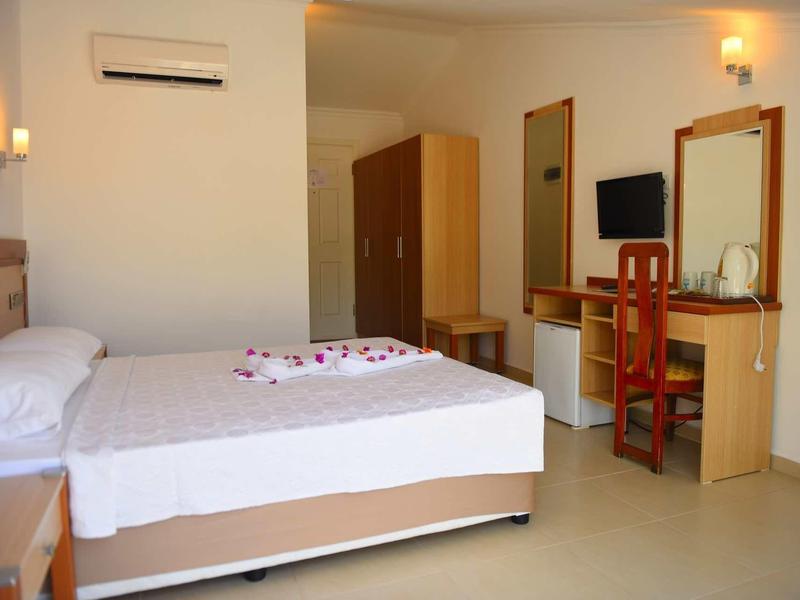 Lichte hotelkamer met tweepersoonsbed, kledingkast, spiegel, stoel en bureau.