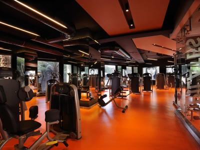 Palestra moderna con pavimento arancione e varie attrezzature da allenamento.