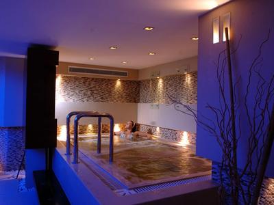 Area benessere illuminata con jacuzzi e decorazione murale