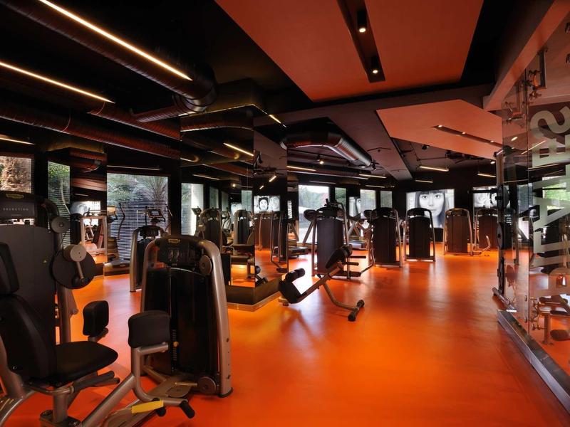 Palestra moderna con pavimento arancione e varie attrezzature per l'allenamento.