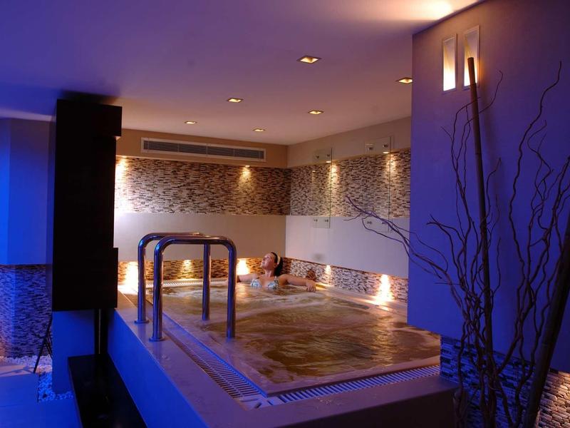 Area benessere illuminata con jacuzzi e decorazione murale