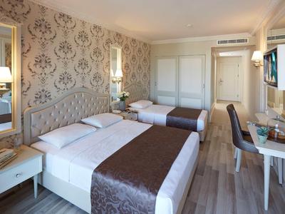 Moderní hotelový pokoj se dvěma postelemi, stolem, TV a elegantním dekorem.