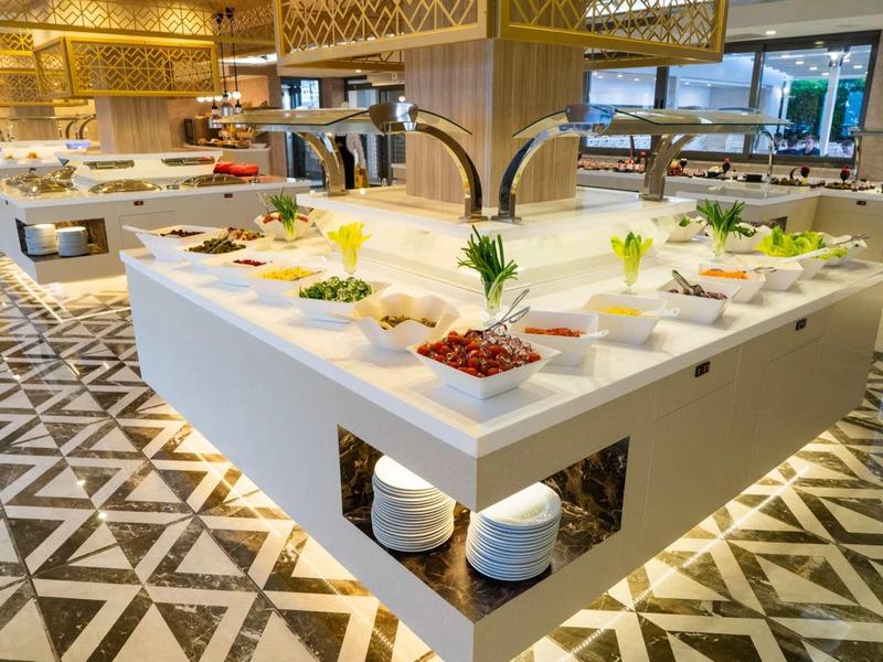 Brightly lit buffet area in modern hotel with various dishes and geometric floor pattern.