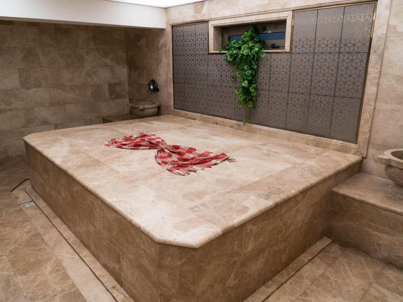 Modern hammam with marble slabs and red flower petals as decoration.